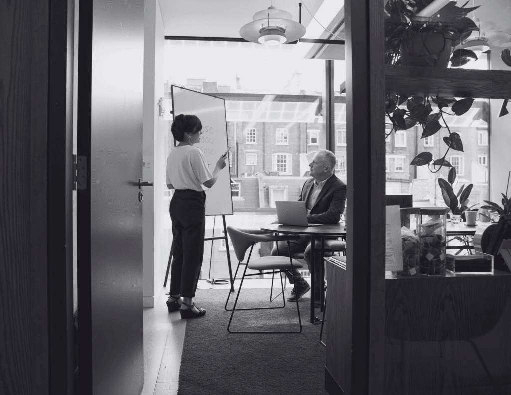 a CEO and a chief of staff, writing on a whiteboard.