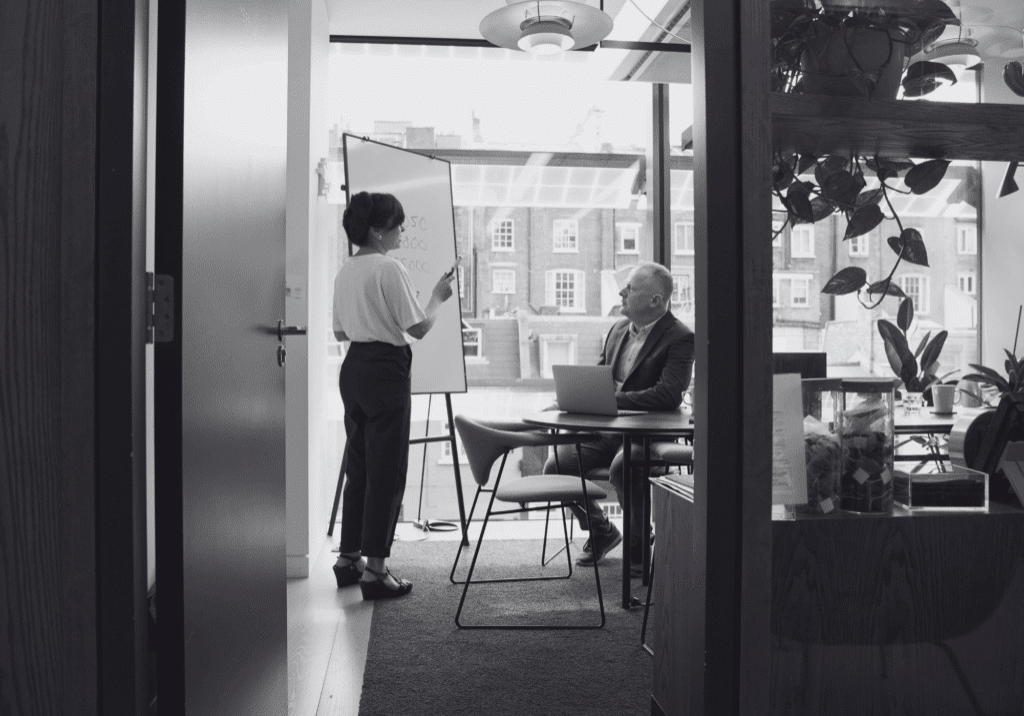 a CEO and a chief of staff, writing on a whiteboard.